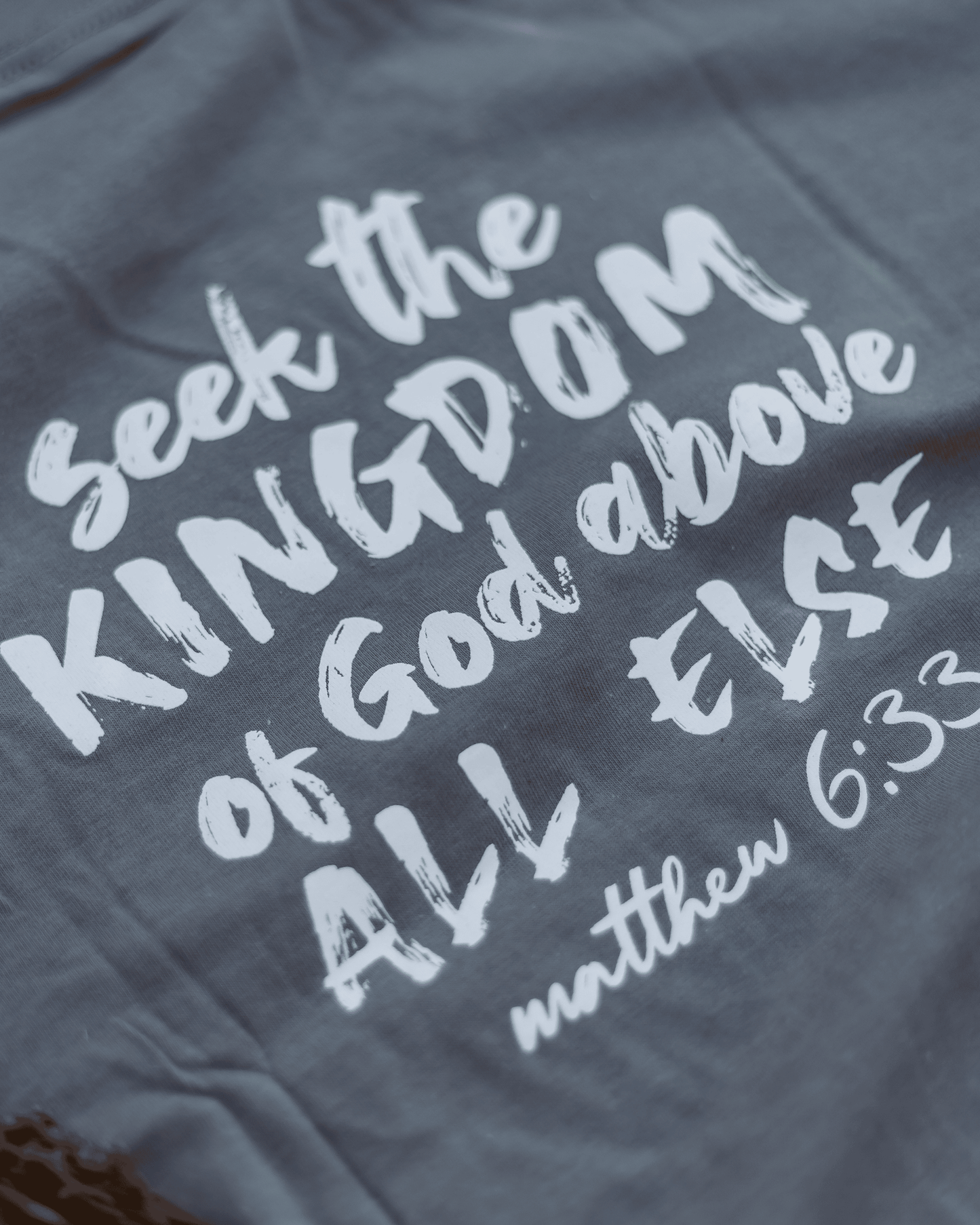 Gray t-shirt with white text 'Seek the Kingdom of God above all else' from Matthew 6:33