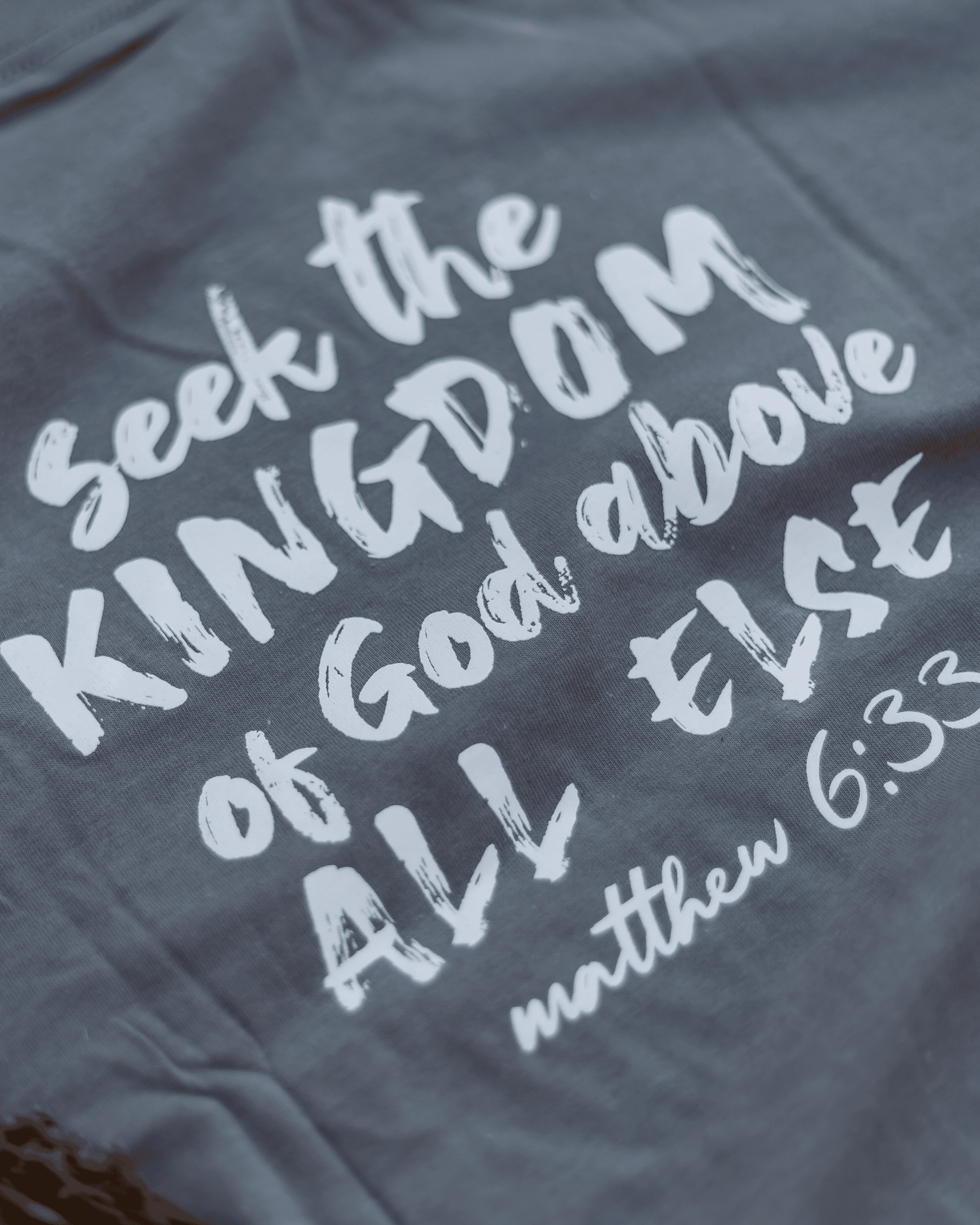 Gray t-shirt with white text 'Seek the Kingdom of God above all else' from Matthew 6:33